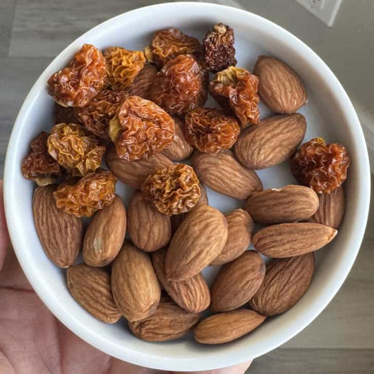 White bowl with almonds and golden berries.