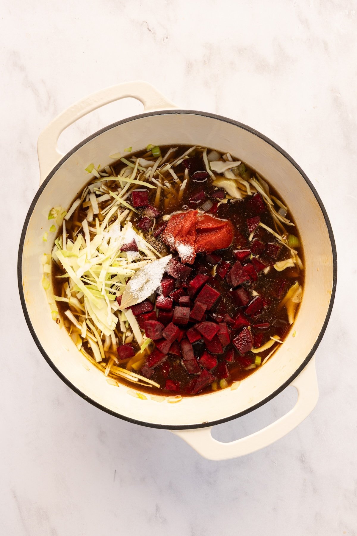 adding beets, cabbage, and broth to Dutch oven