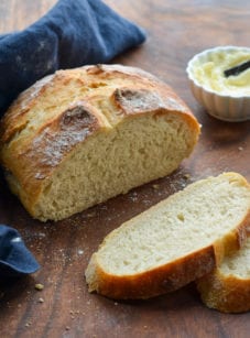 Partially-sliced loaf of crusty artisan bread.