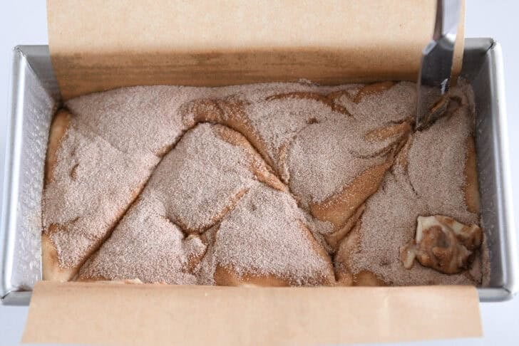 Using butter knife to swirl cinnamon and sugar into vanilla quick bread.
