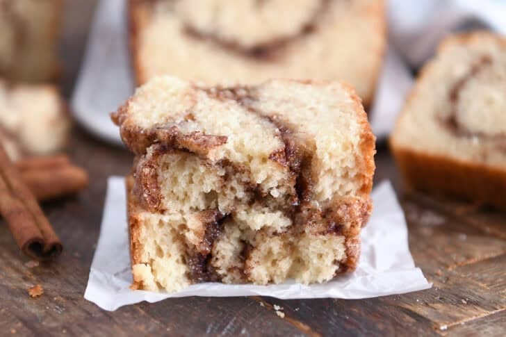Two half slices of cinnamon swirl quick bread stacked on white parchment paper.