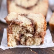 Two half slices of cinnamon swirl quick bread stacked on white parchment paper.