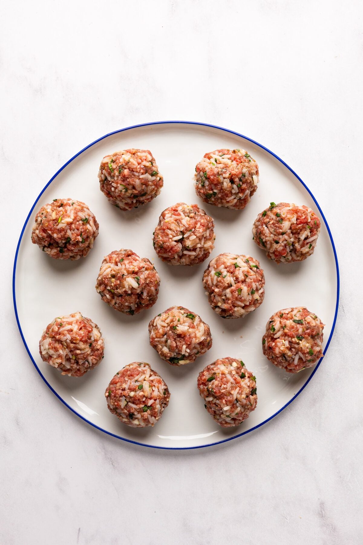 white plate with 12 uncooked meatballs