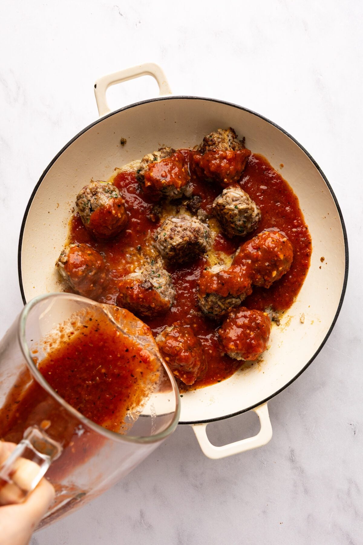 pouring the sauce over the albondigas