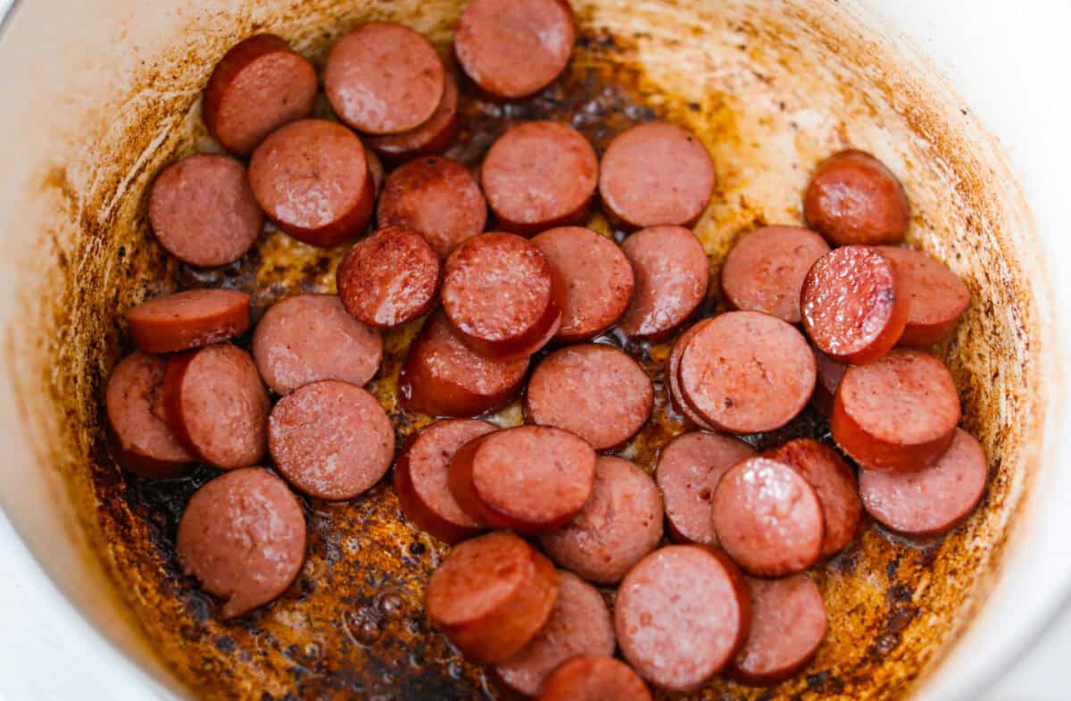 Sausage slices cooking in a large pot.