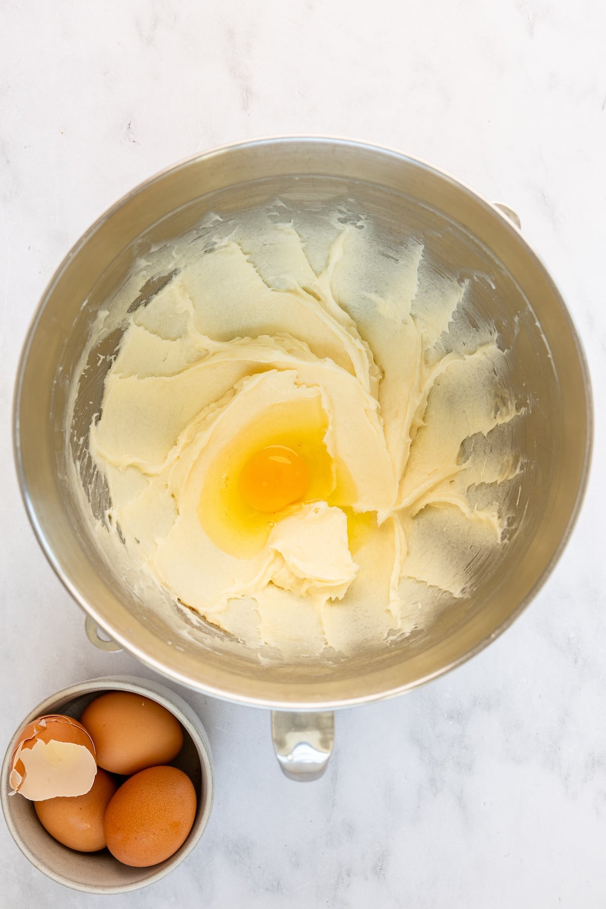 mixing bowl with eggs added to vanilla, butter, cream cheese, and sugar mixture