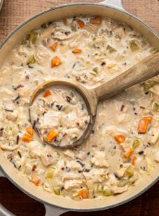chicken and wild rice soup in Dutch oven with wooden spoon
