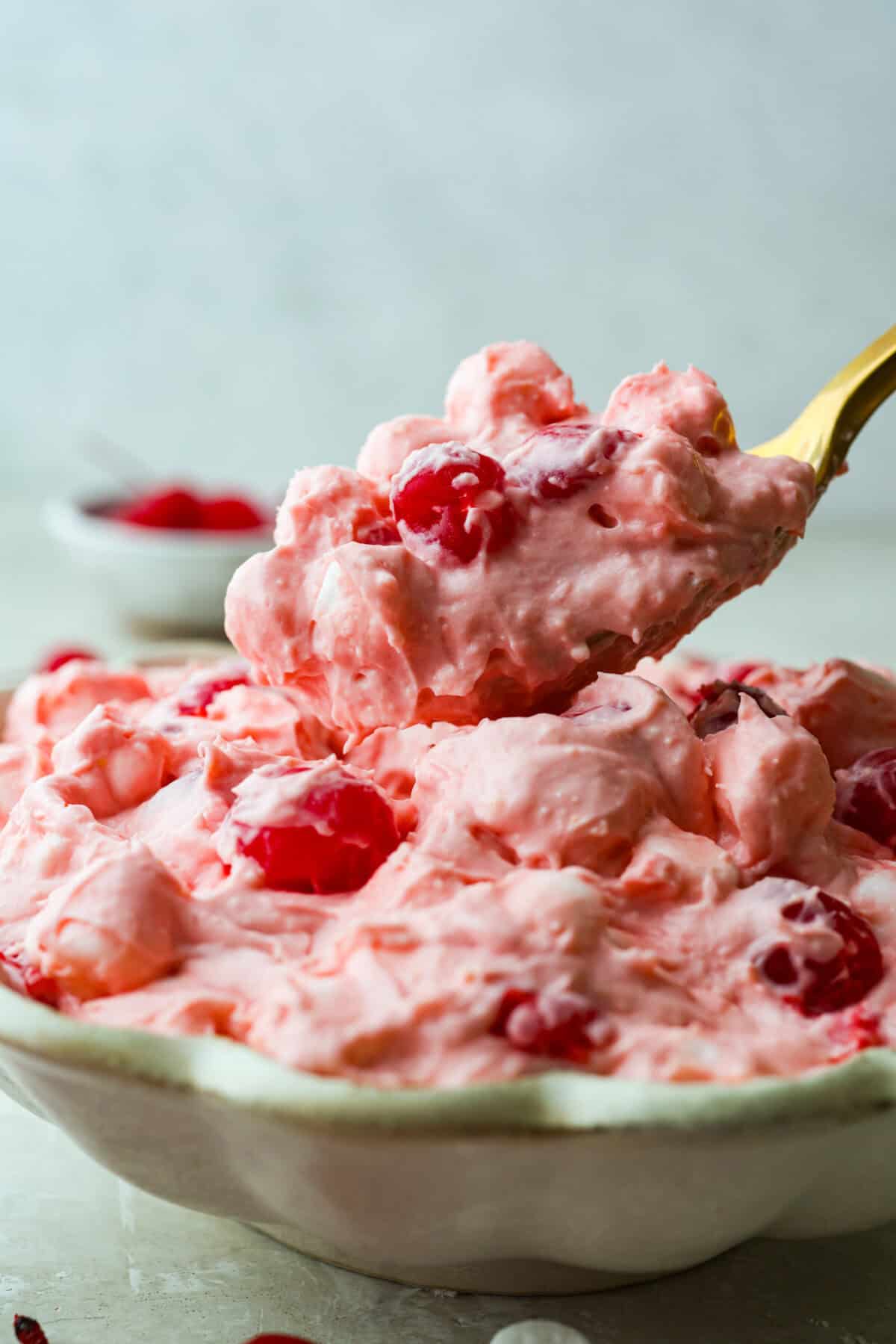 Someone getting a scoop of cherry cheesecake fluff out of the bowl. 