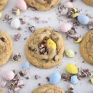 Baked cookies on parchment paper with crushed and whole cadbury eggs scattered around.