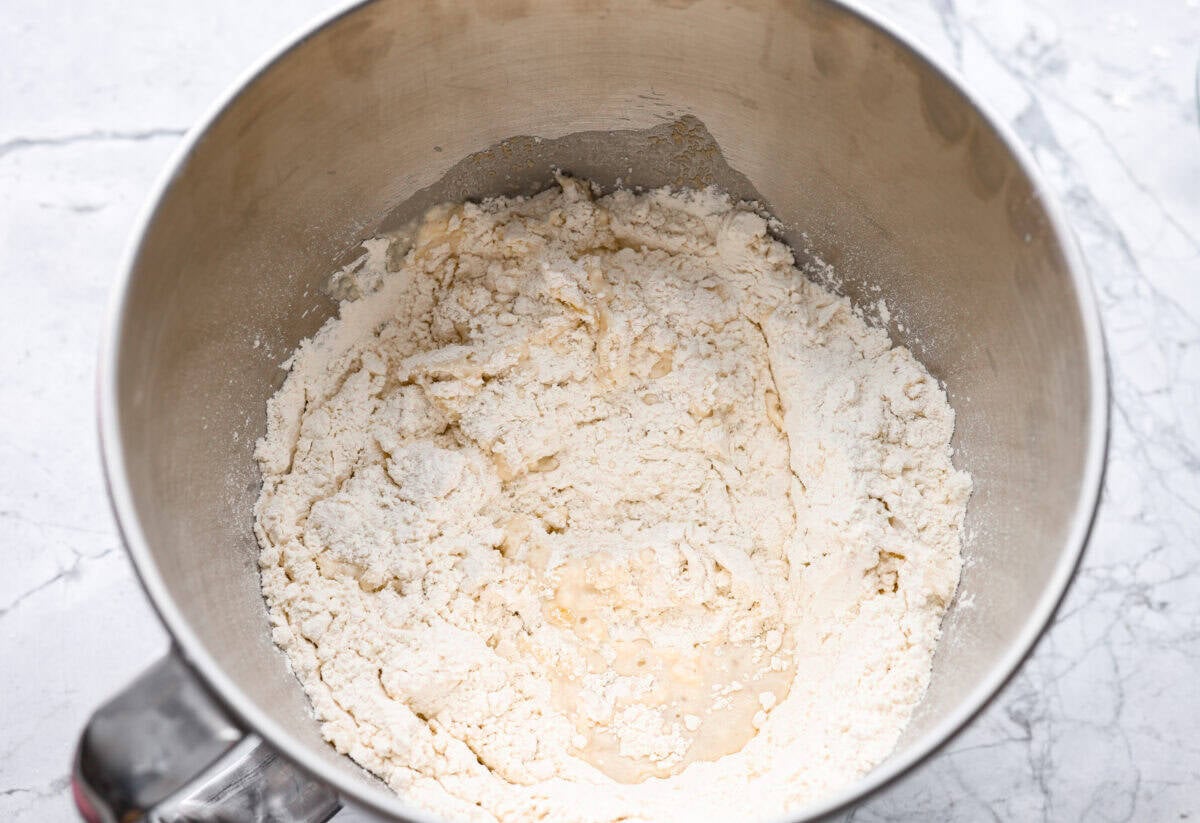 Warm water, yeast, sugar oil, salt, and flour all added to the bowl of a stand mixer. 