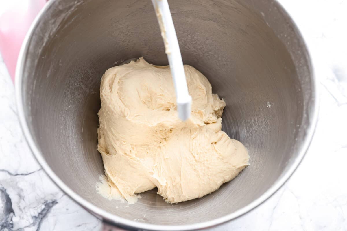 French bread rolls dough ball in the bottom of the bowl of a stand mixer. 