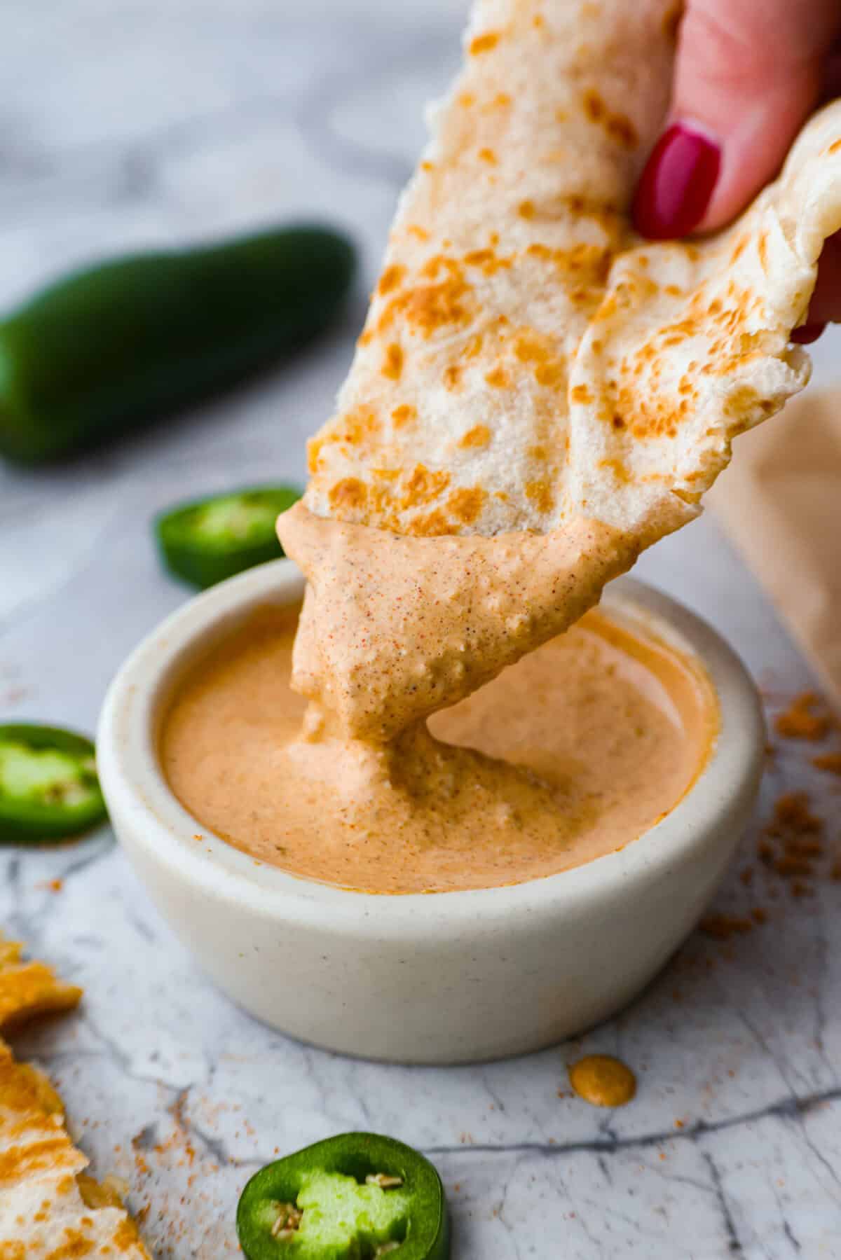 Someone dipping a quesadilla into the Taco Bell quesadilla sauce. 