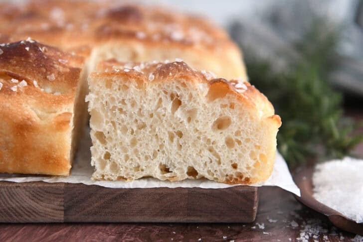 Square piece of fluffy focaccia bread on white parchment paper.