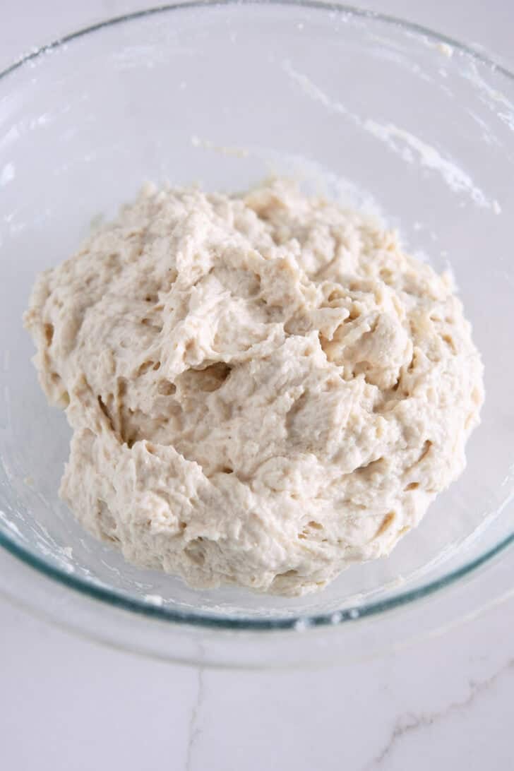 Shaggy mixture of focaccia dough in glass bowl.