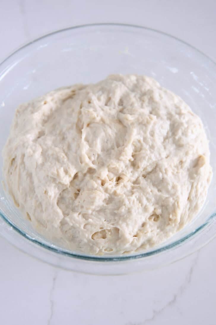 Shaggy mixed focaccia dough in glass bowl.