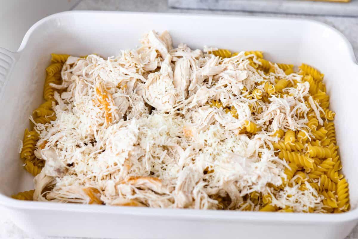 Pasta and shredded chicken in a baking dish. 