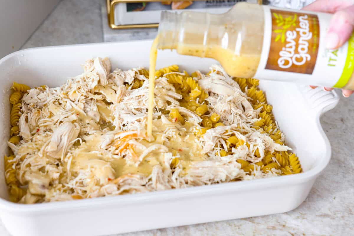Someone pouring Olive Garden dressing over the chicken and pasta. 