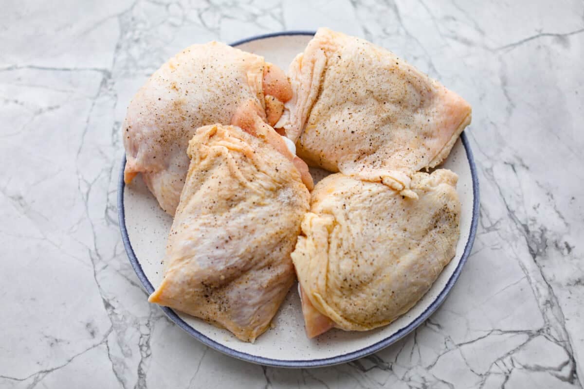 Chicken thighs seasoned with salt and pepper. 