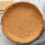 finished graham cracker crust with graham crackers, butter and sugar nearby