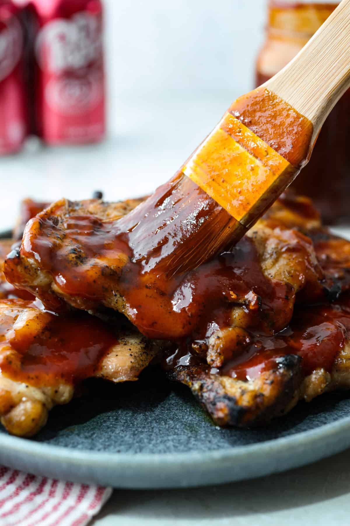 Someone spreading Dr Pepper BBQ sauce on some grilled chicken.