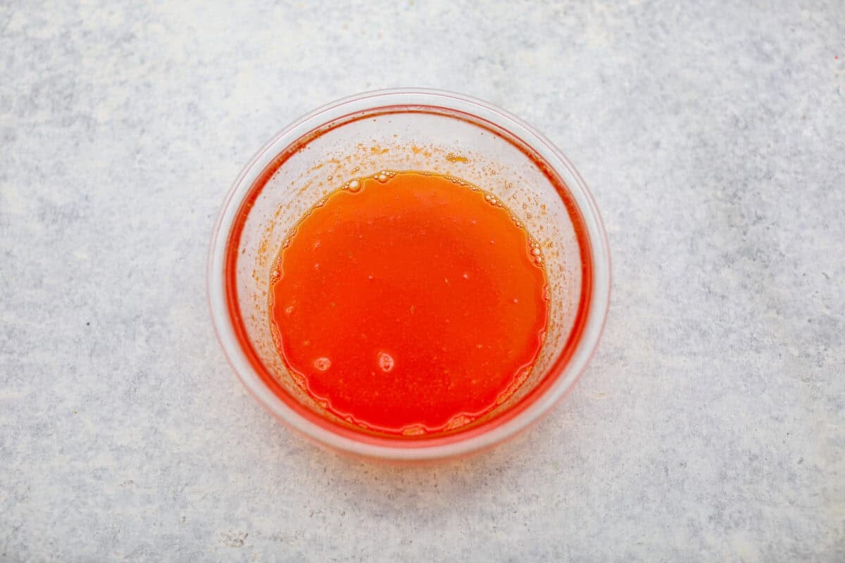 Orange gelatin, orange zest and orange juice mixed together in a bowl. 