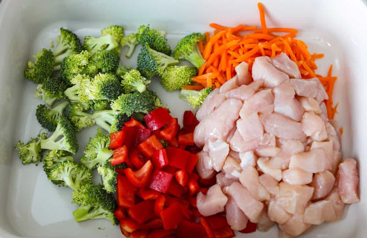 Chopped veggies and diced chicken in a baking dish. 
