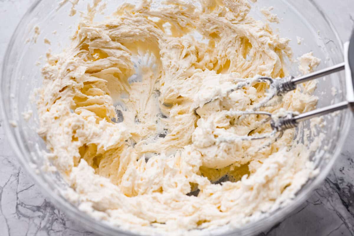 Cream cheese and butter mixed together in a mixing bowl with a hand mixer. 