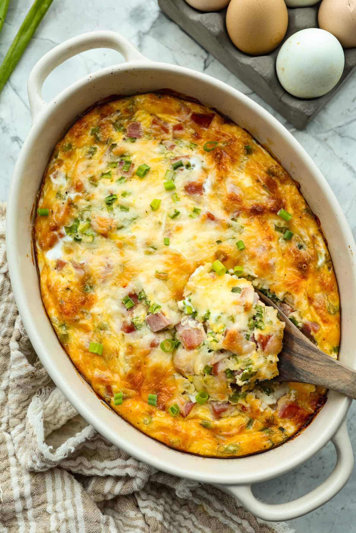 Baked farmer's casserole with a wooden spoon scooping out a serving. 