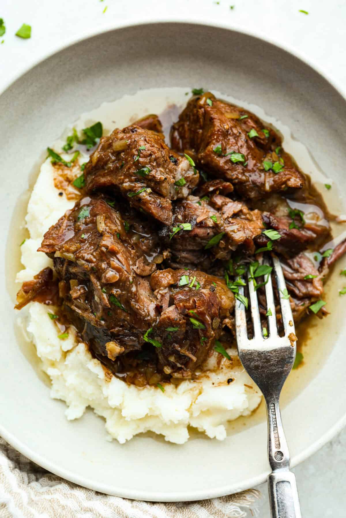 Plate of mashed potatoes topped with 3 ingredient butter beef. 