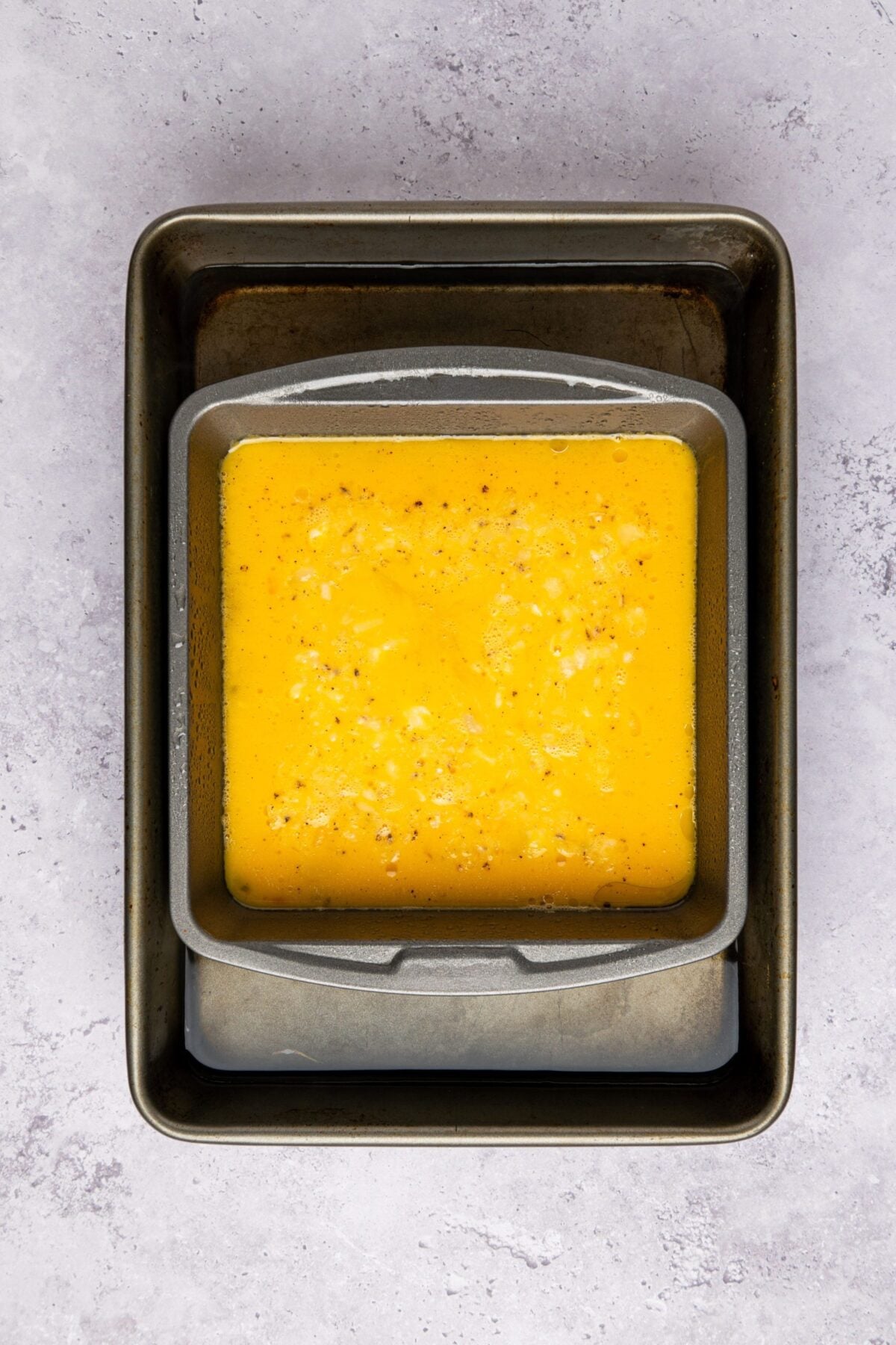 egg mixture in square pan placed inside a water bath in a roasting pan