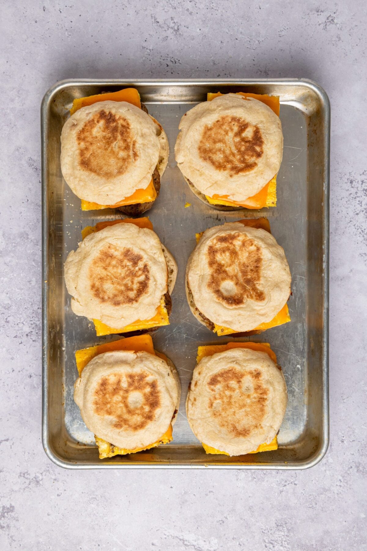 Six assembled egg sandwiches on a baking sheet.