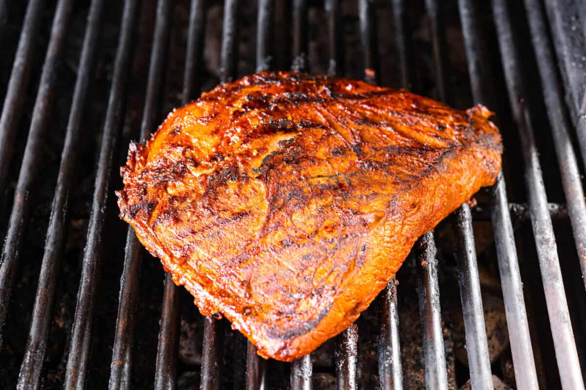 Marinated steak cooking on the grill. 