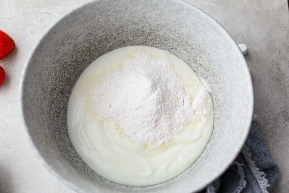 Mixing bowl with vanilla yogurt and pudding mix added to it. 