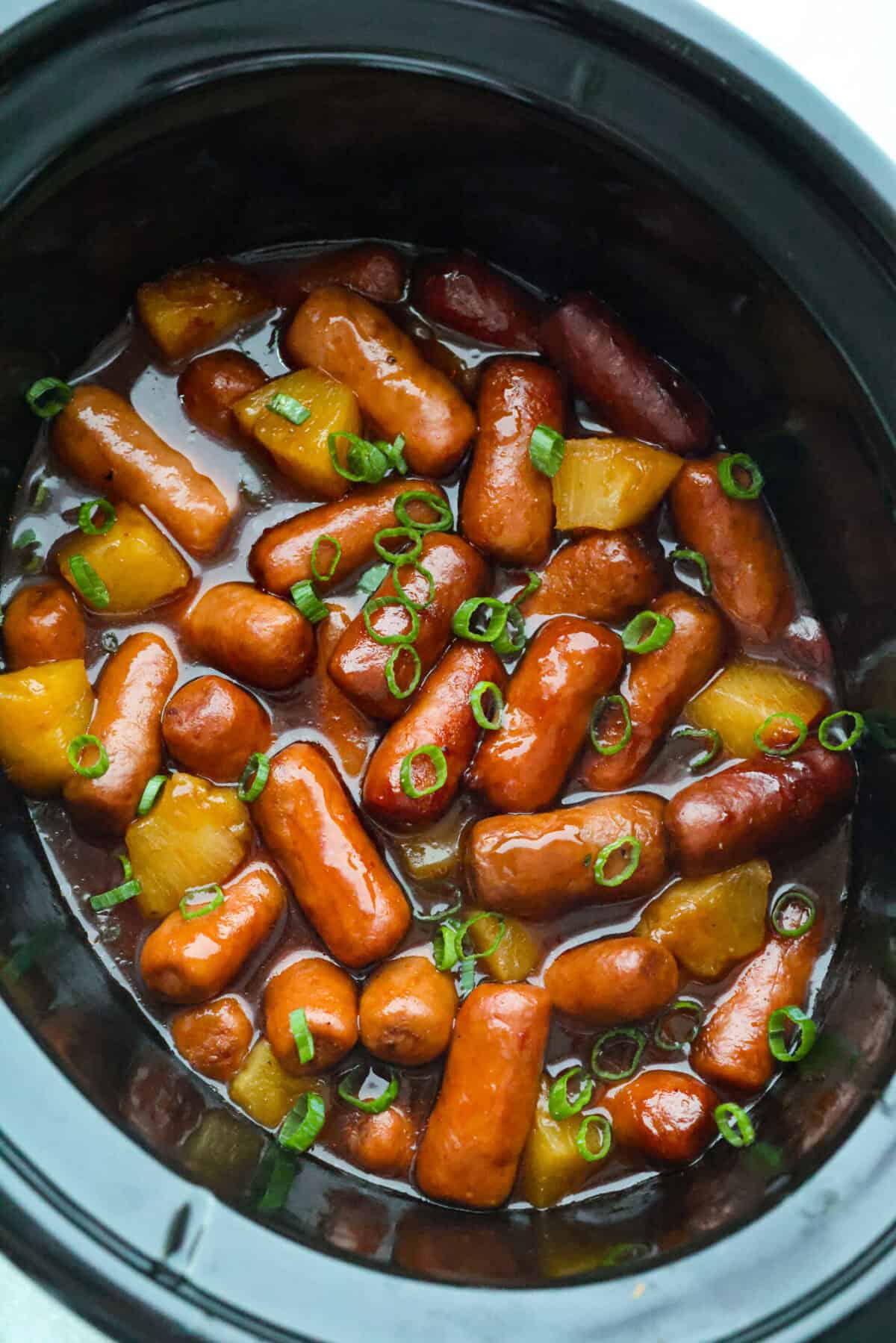 Overhead shot of the hawaiian little smokies in a slow cooker. 