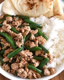Top down view of ground turkey, green beans, rice and naan bread in white bowl.