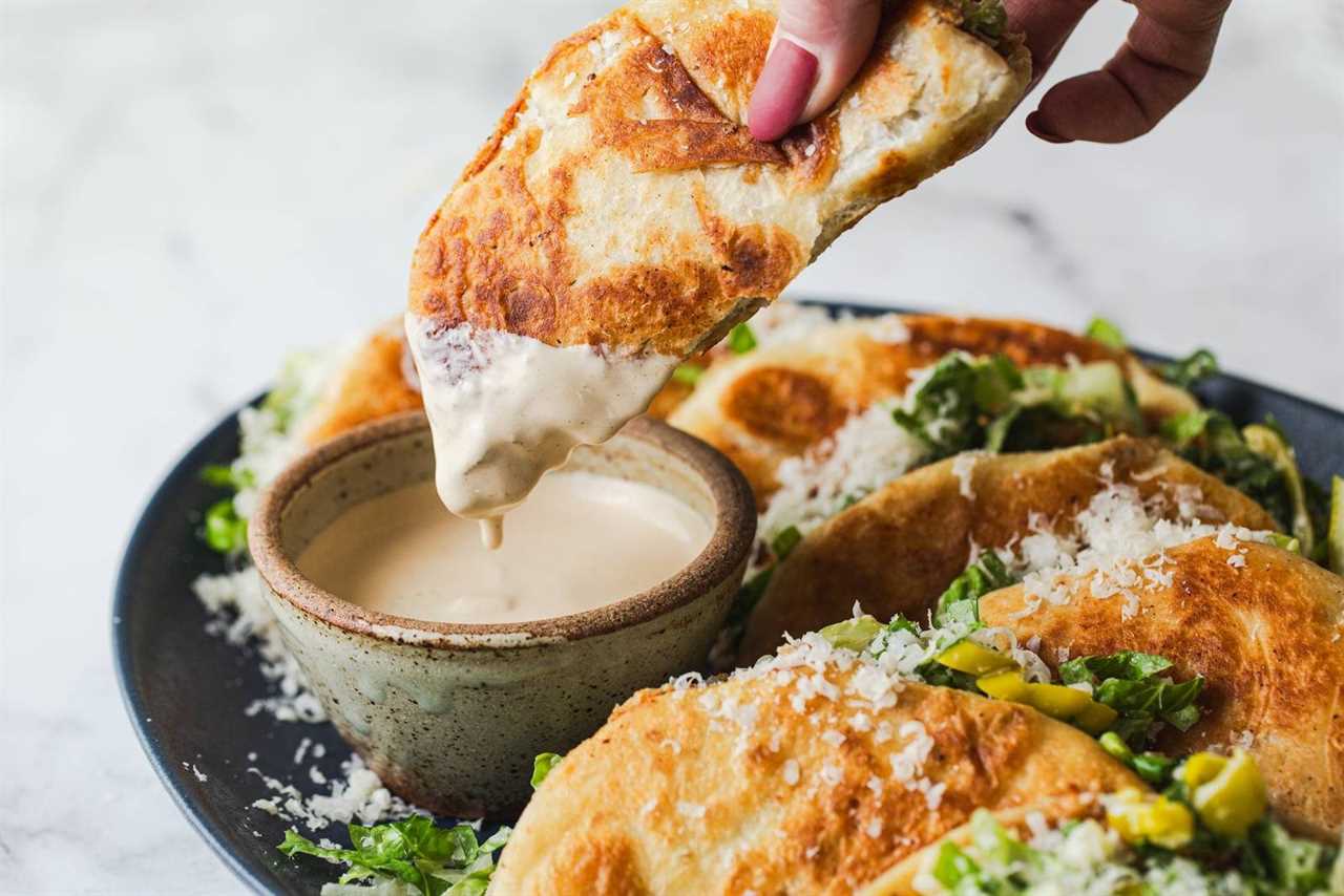 Dipping smash tacos into caesar dressing.