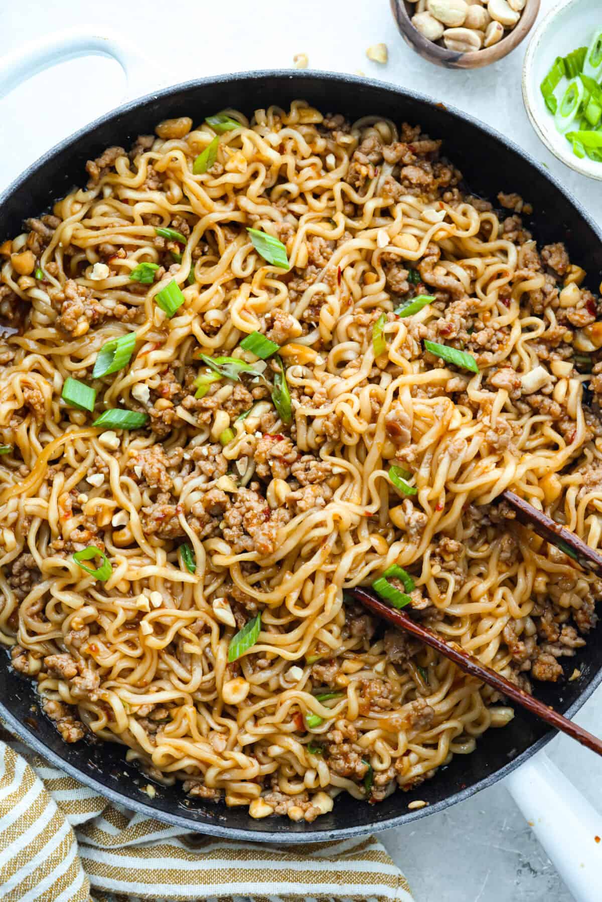 Pan of dragon noodles topped with sliced green onions.
