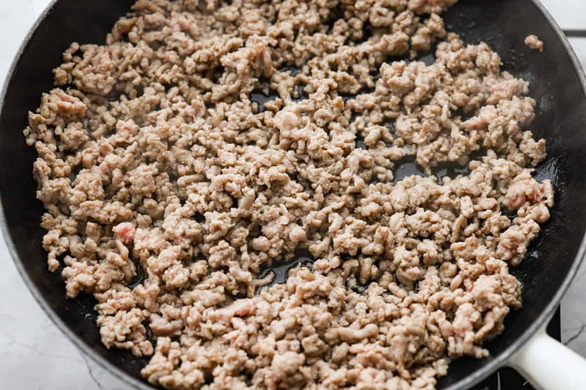 Ground pork cooking in a skillet.