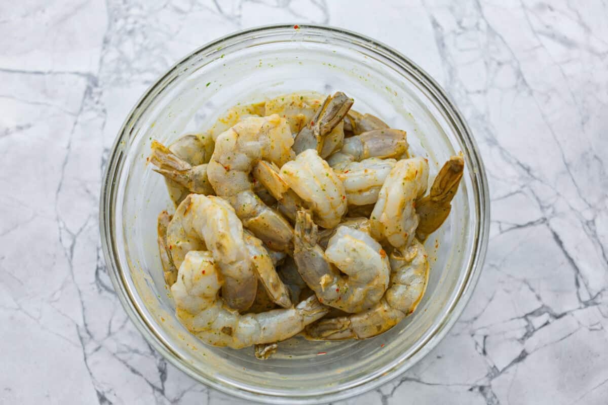 Raw shrimp in a bowl covered in the dressing as a marinade. 