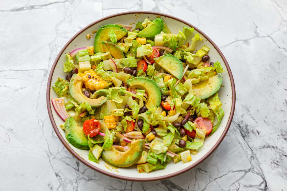 Salad ingredients added to a large serving bowl. 