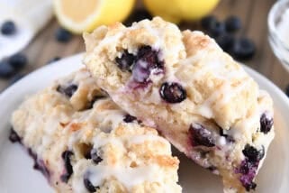 Two triangle-shaped baked lemon blueberry scones on white plate.