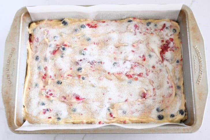 Cake batter with fresh berries spread in 9X13-inch pan and topped with sugar.