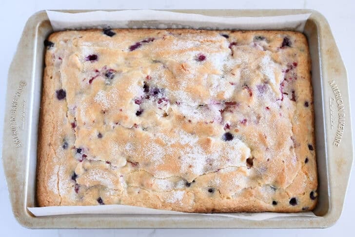 Baked cake with fresh berries spread in 9X13-inch pan and topped with sugar.