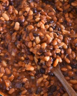 Wooden spoon scooping up calico baked beans.