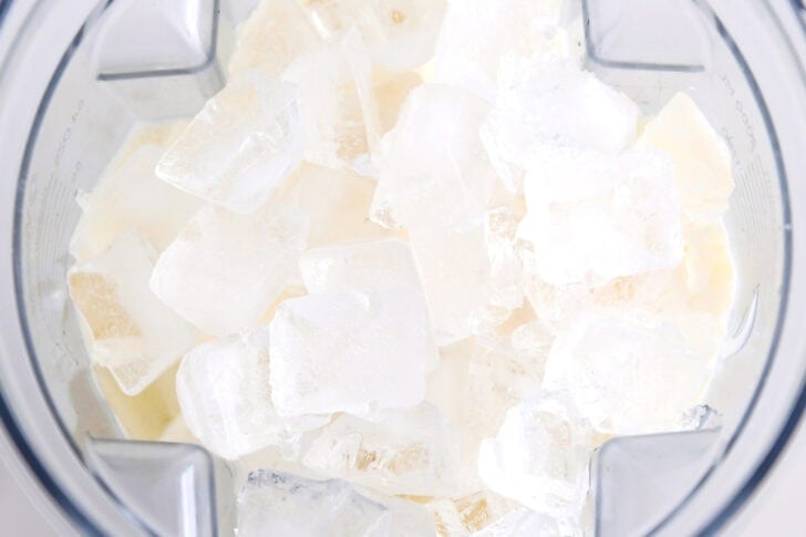 Cubed ice in blender with pina colada ingredients.