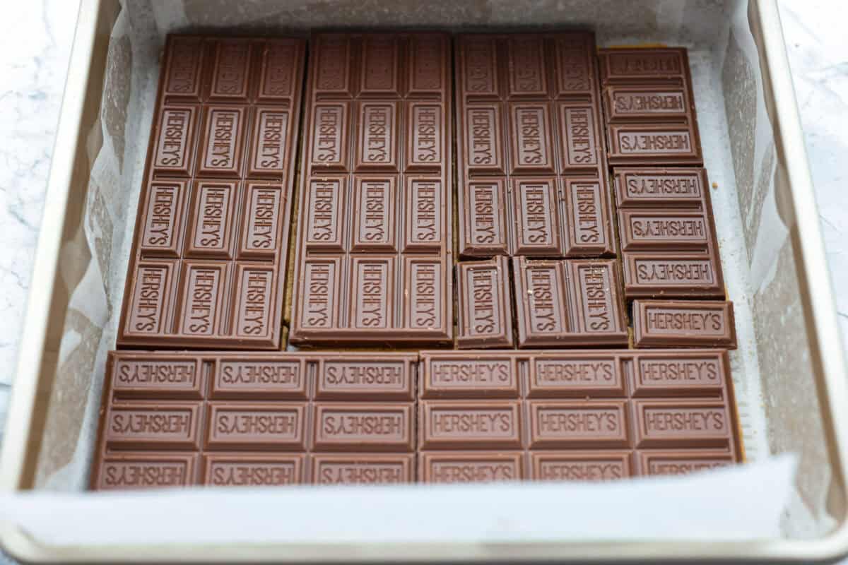 Chocolate bar pieces spread evenly over the graham cracker layer. 