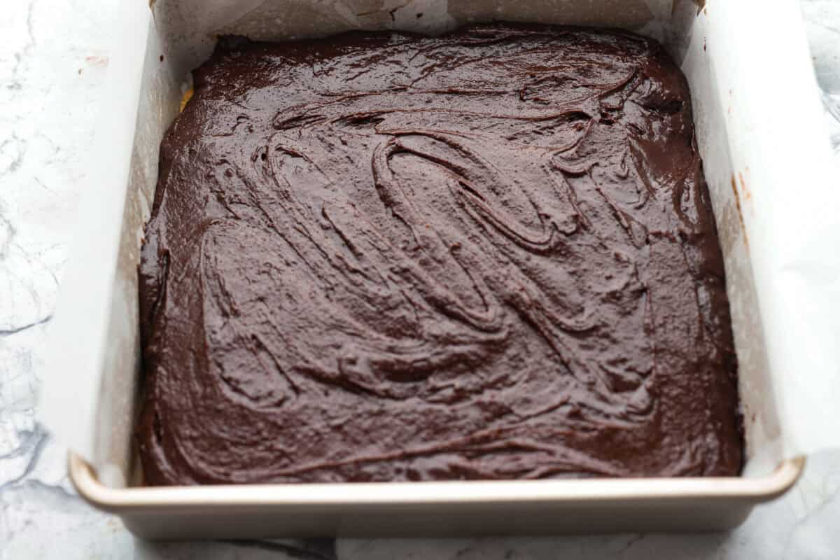 Brownie batter spread evenly over the chocolate bar pieces. 