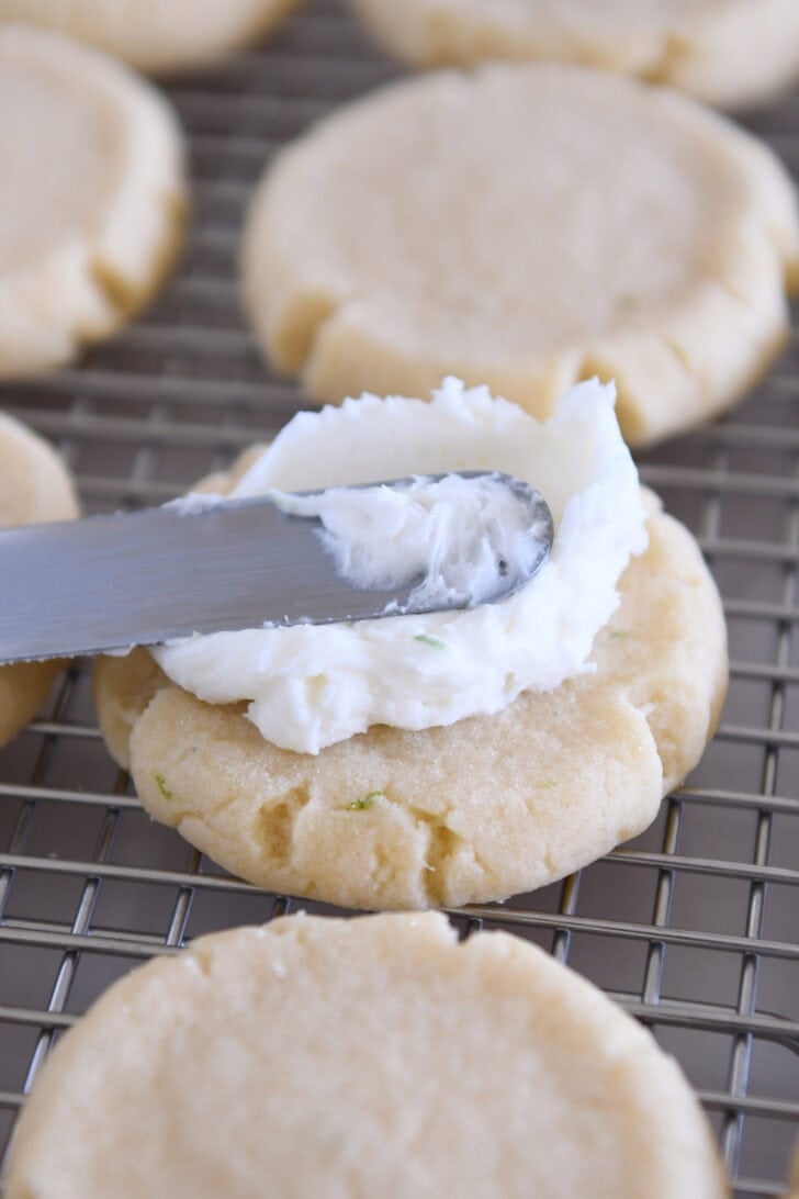 Frosting round sugar cookie with coconut lime frosting.