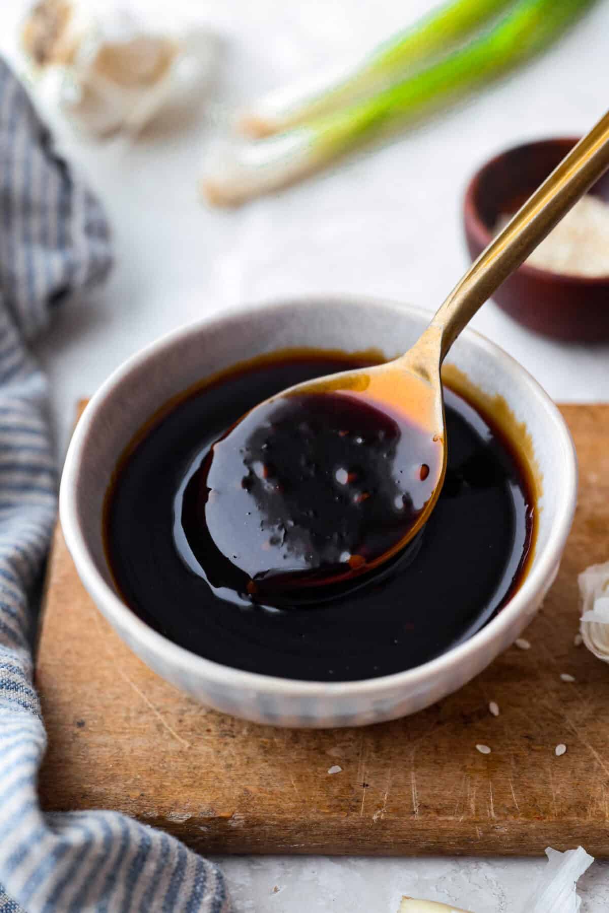 Small bowl of teriyaki sauce with gold spoon. 