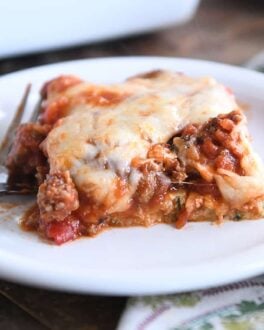 serving of cheesy zucchini spaghetti casserole on white plate with fork